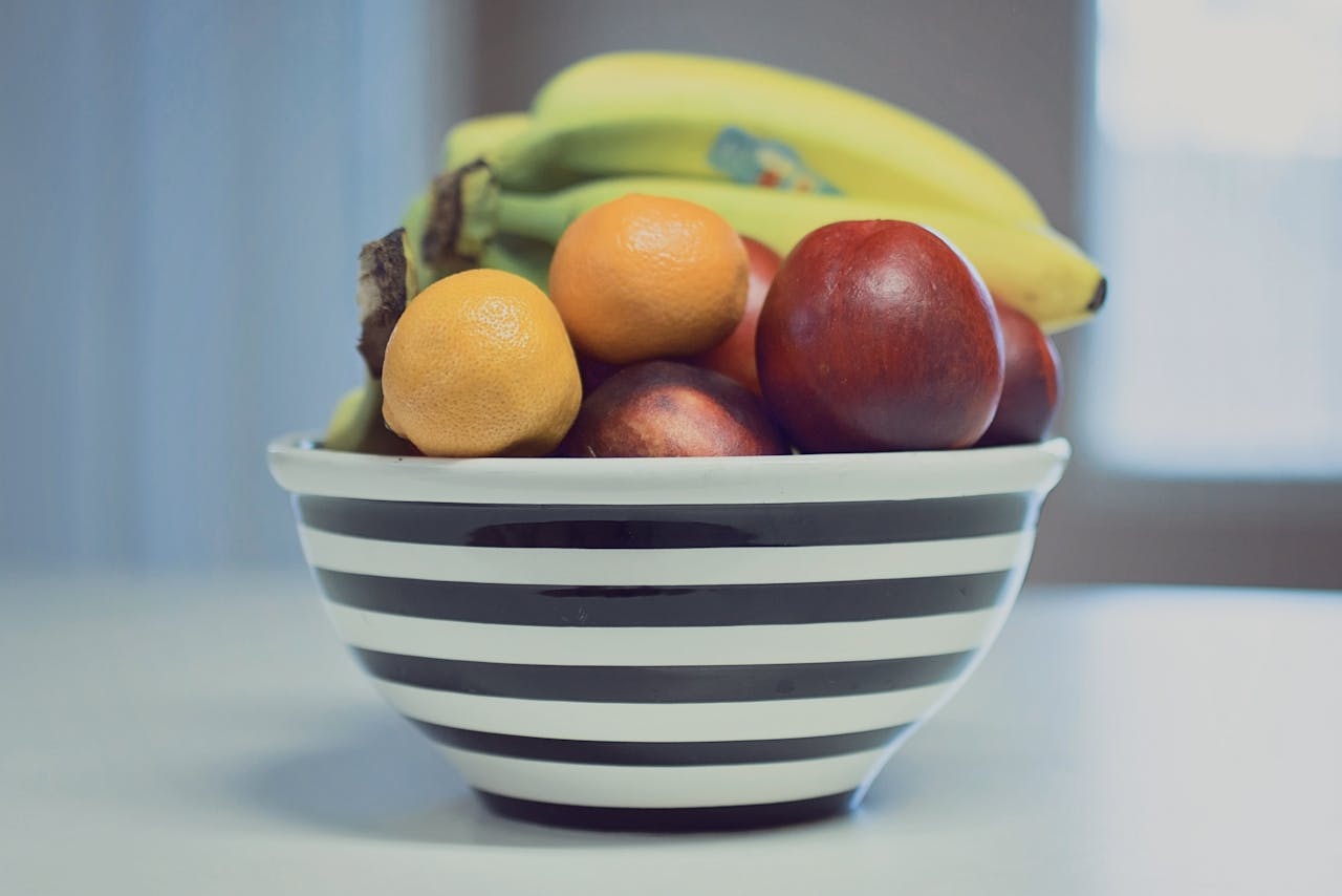 A vibrant assortment of fresh fruits in a striped bowl, ideal for healthy living.