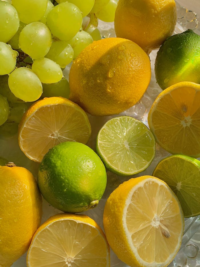 Close-up of fresh lemons, limes, and grapes in sunlight showcasing tropical freshness.