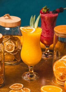 Colorful tropical and berry cocktails with fresh and dried fruit slices, perfect for a refreshing summer drink.